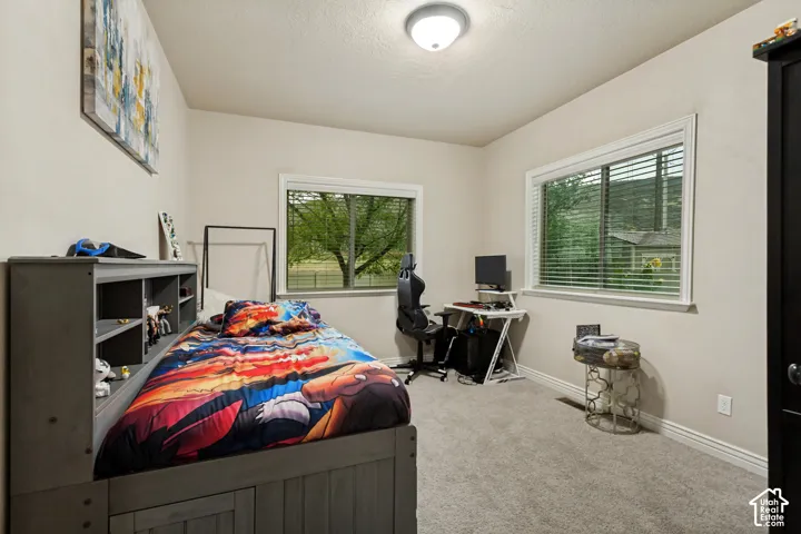 Room featuring neutral wall tones, wall-to-wall carpeting, and two windows with horizontal blinds