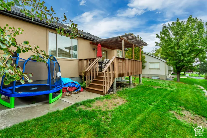 Elevated wood deck featuring a pergola, wood railings, and a staircase leading to a concrete patio