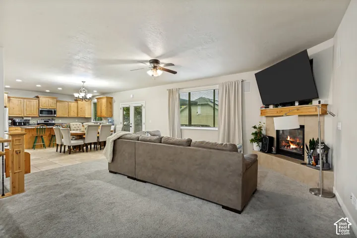 Open concept living area featuring a fireplace with a tile surround and wood mantel, recessed lighting, ceiling fan, and cabinetry with an integrated breakfast bar
