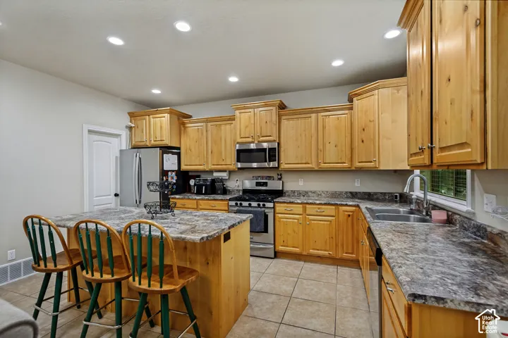 Kitchen featuring natural wood cabinetry, stone-patterned laminate countertops, central island, tiled flooring, and recessed ceiling lighting