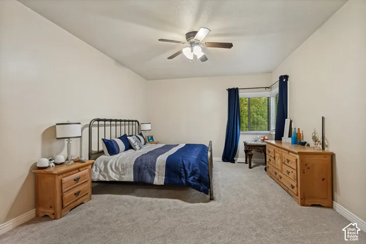 Bedroom featuring neutral wall paint, wall-to-wall carpeting, a multi-pane window, and a ceiling fan with integrated light fixture