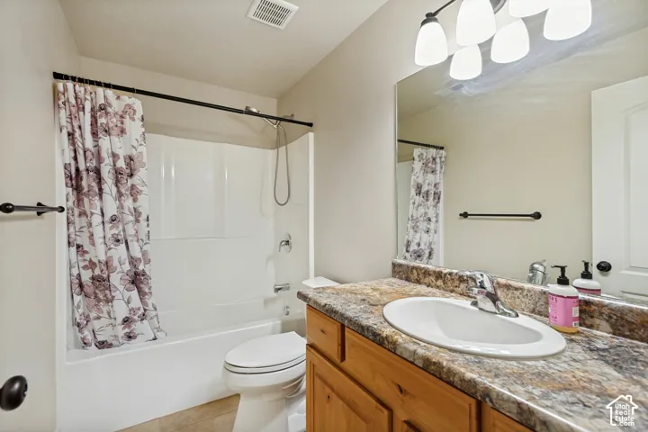 Bathroom featuring a wood-finish vanity with a stone-patterned countertop, an integrated oval sink, a wall-to-wall mirror, and a tub-shower combination with a surround