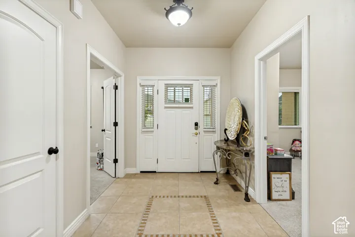Entryway featuring a decorative tile floor with a central border inlay, a white-paneled entry door with sidelights, and a flush-mount light fixture
