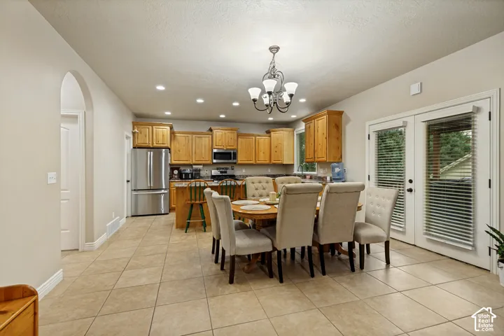 Kitchen featuring stained wood cabinetry, recessed lighting, tile flooring, stainless steel refrigerator, and glass-paneled double doors