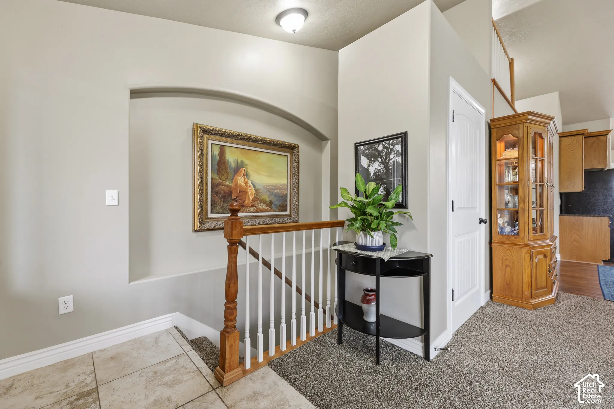Entryway featuring tile flooring, an arched wall niche, and a staircase with a wooden handrail and white balusters