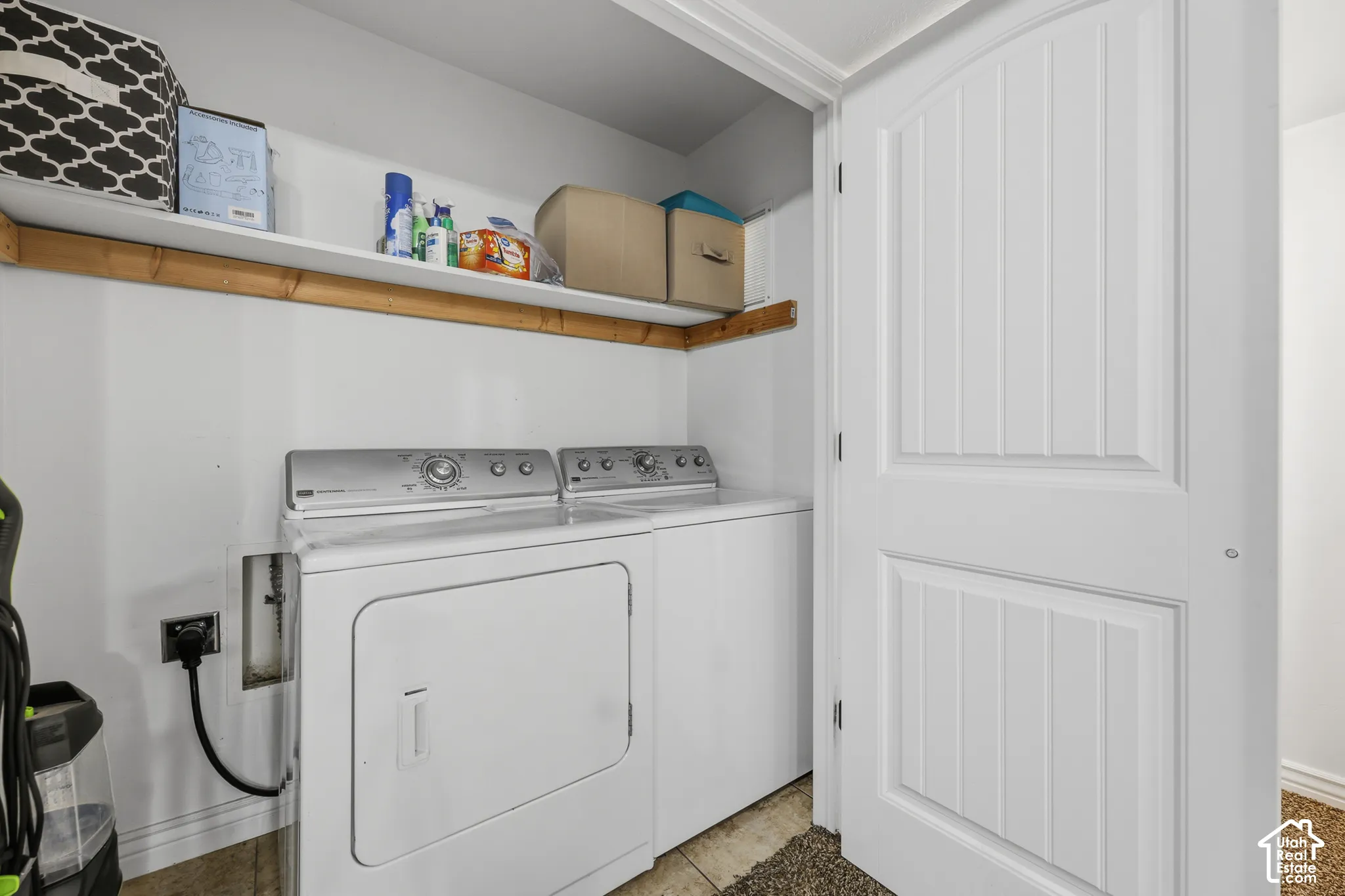 Laundry area featuring tile flooring, built-in wooden shelving, and a two-panel interior door