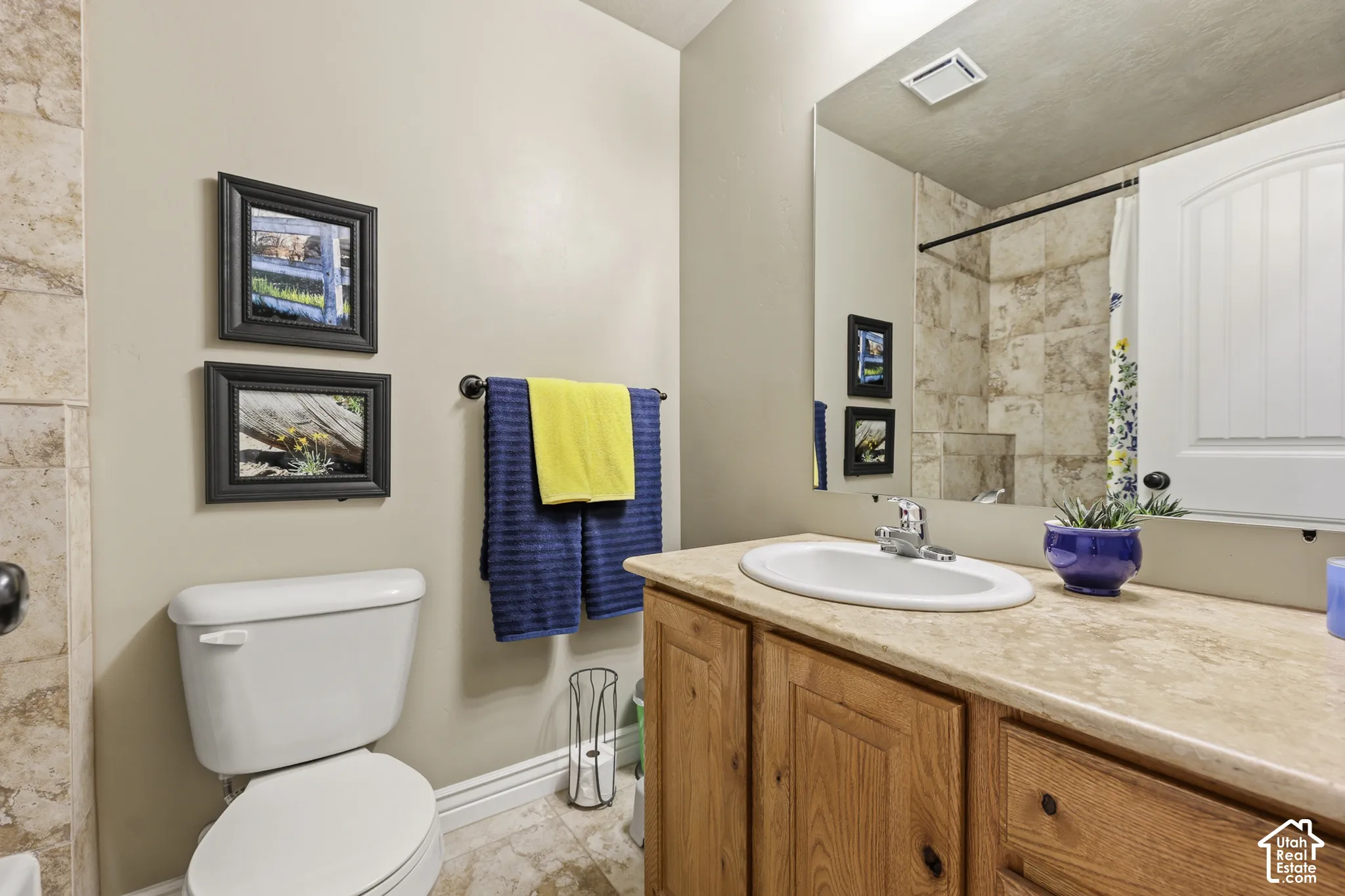Bathroom featuring a vanity with wood cabinetry, stone-surface countertop, an oval undermount sink, and a full-width wall mirror