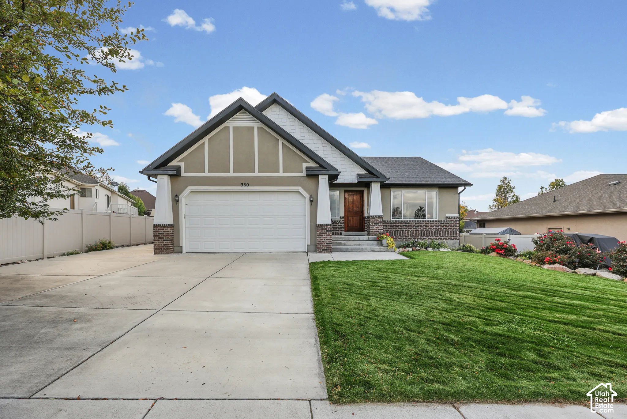 Craftsman-inspired exterior featuring stone veneer accents, multi-gabled roofline, decorative timber framing, concrete driveway, and manicured lawn