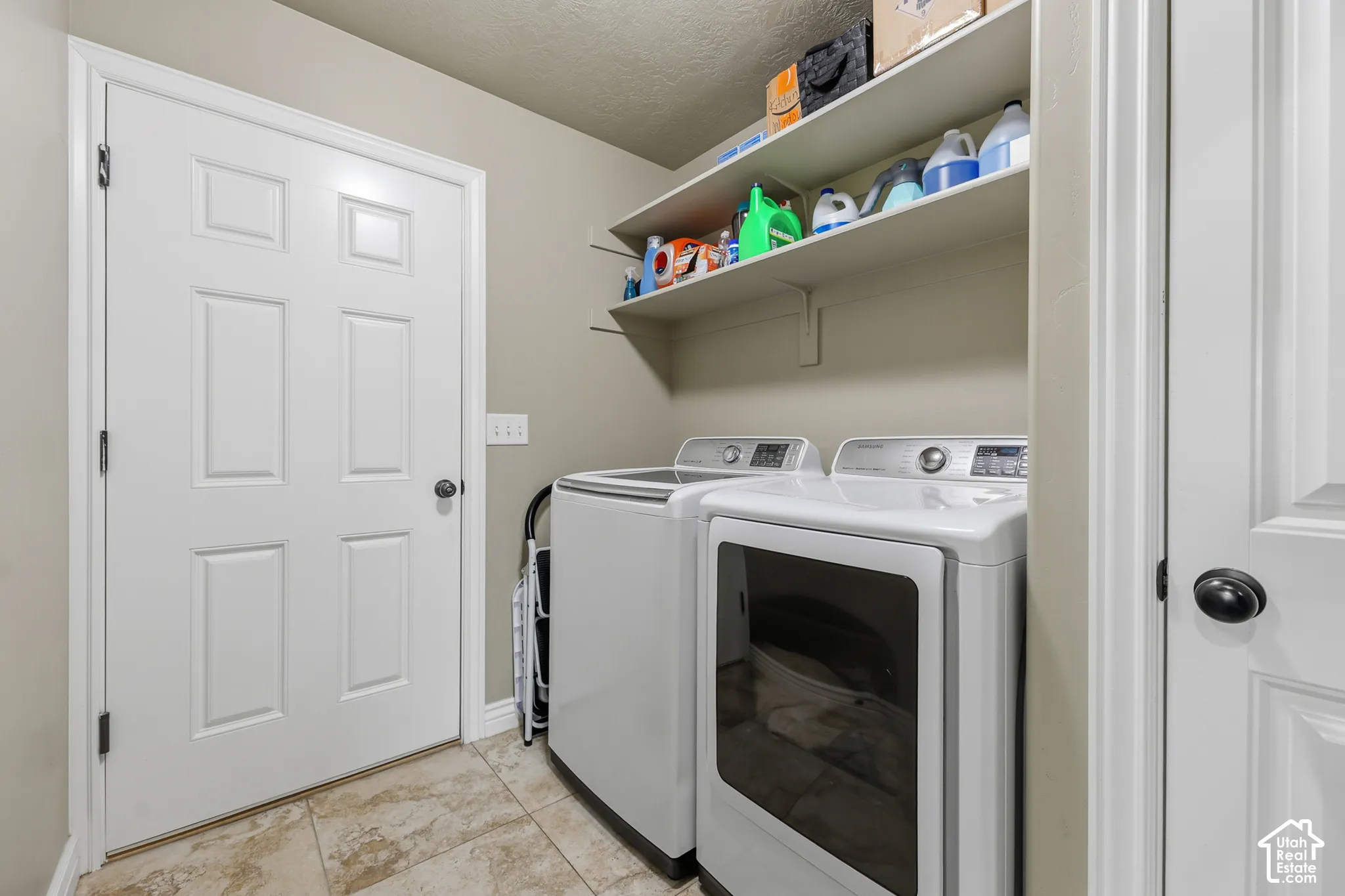 Laundry room featuring tile flooring, six-panel interior doors, and wall-mounted shelving