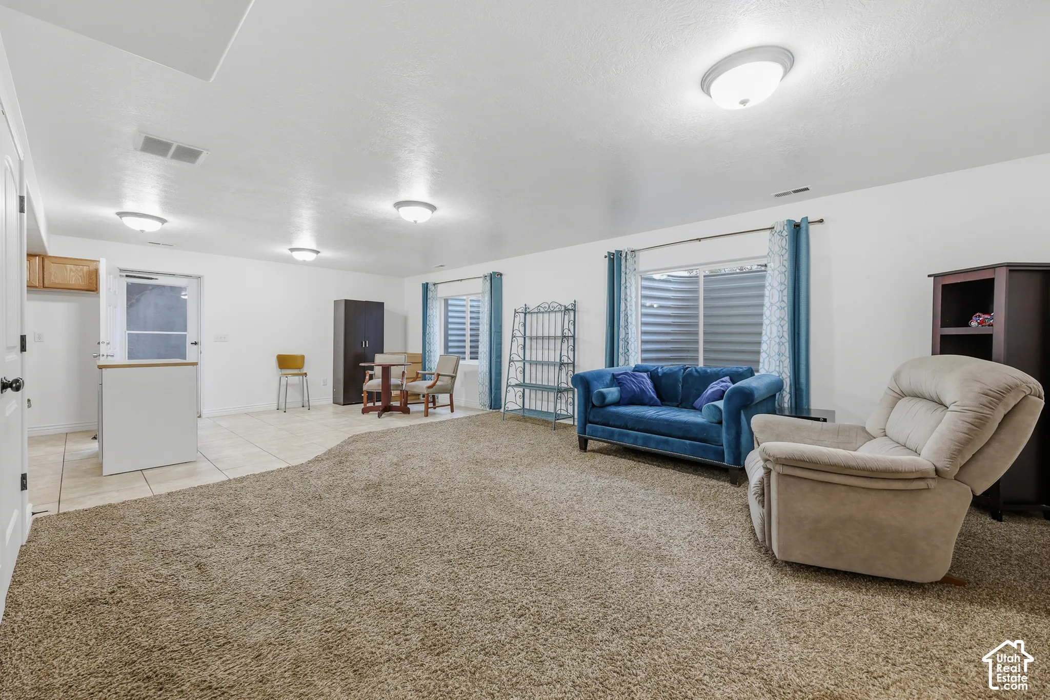 Open floor plan featuring carpeting, tile flooring, recessed and flush-mount lighting, and egress-style windows