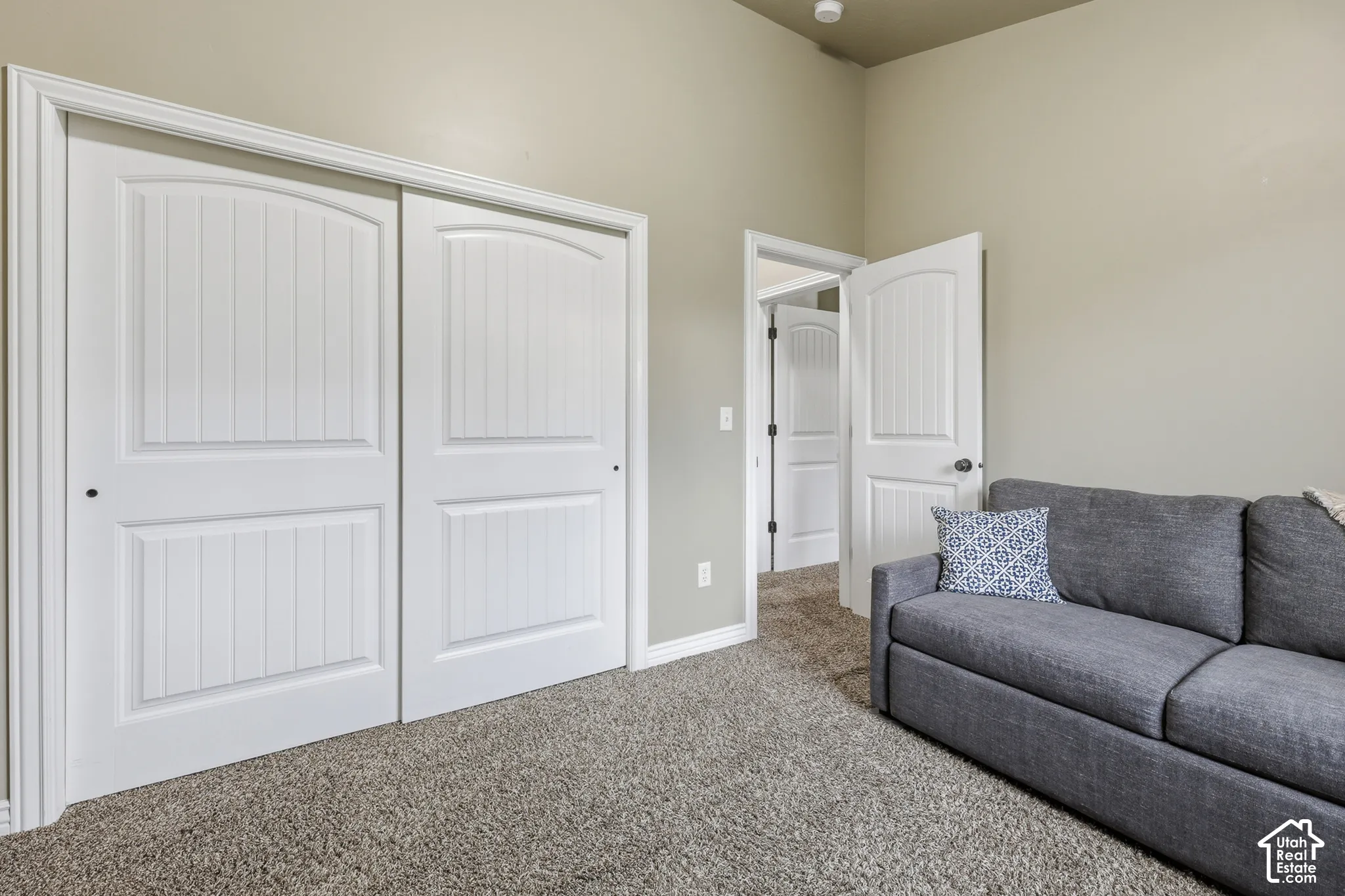 Room featuring high ceilings, wall-to-wall carpeting, sliding panel closet doors, and interior doors with molded detailing