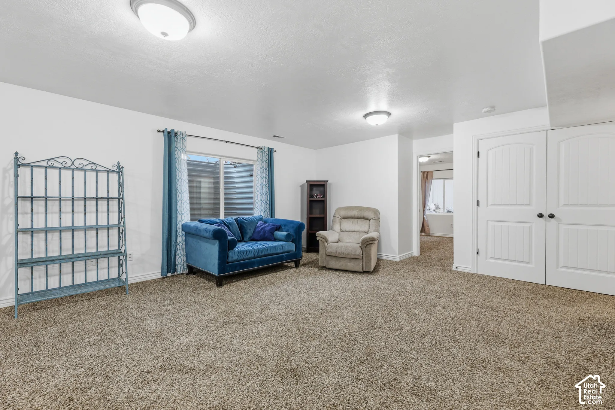 Neutral wall tones, wall-to-wall carpeting, dual flush-mount ceiling light fixtures, a single-window egress assembly, and double-panel doors