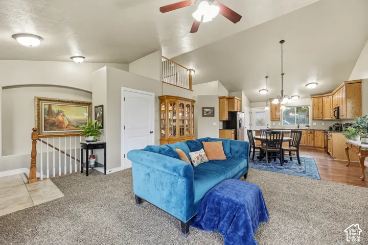 Open-concept interior featuring vaulted ceilings, wood cabinetry, a built-in recessed niche, and a staircase with a wooden handrail and balusters