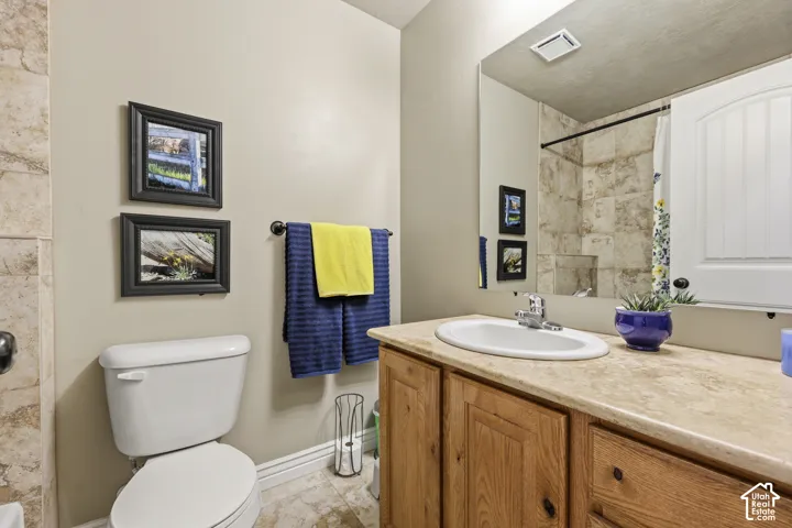 Bathroom featuring a vanity with wood cabinetry, stone-surface countertop, an oval undermount sink, and a full-width wall mirror