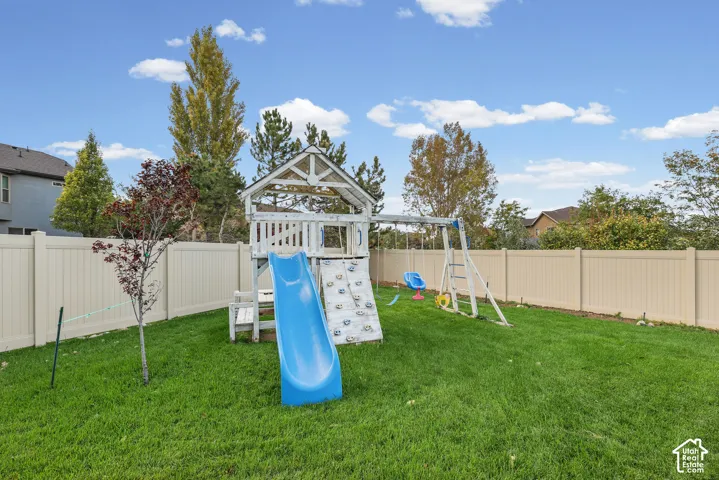 Private backyard featuring a manicured lawn, perimeter vinyl fencing, and mature trees