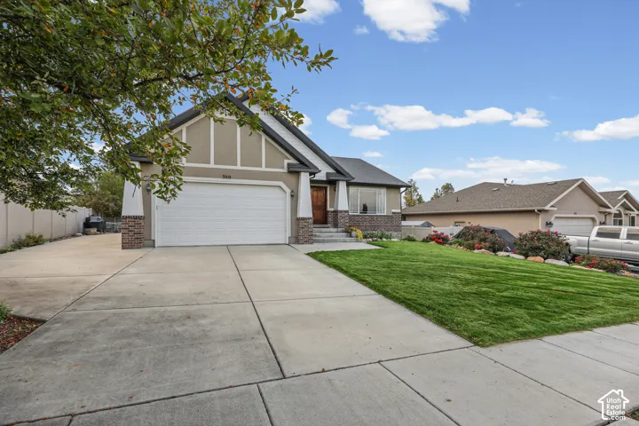 Single-story exterior featuring a brick and stucco facade, timber-style trim, front-facing two-car garage, concrete driveway, and a maintained front lawn