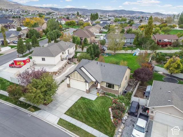 Single-story residence featuring a multi-gabled roof, stone veneer accents, concrete driveway, and a landscaped front yard with mature shrubbery