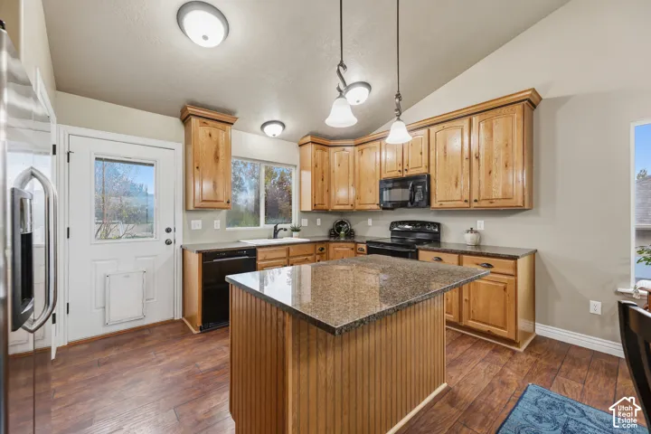Kitchen featuring wood cabinetry, stone countertops, central island, wood-finish flooring, and pendant lighting