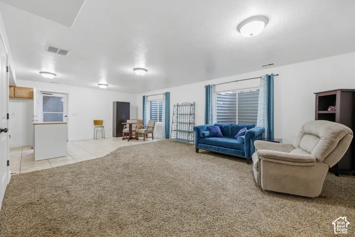 Open floor plan featuring carpeting, tile flooring, recessed and flush-mount lighting, and egress-style windows