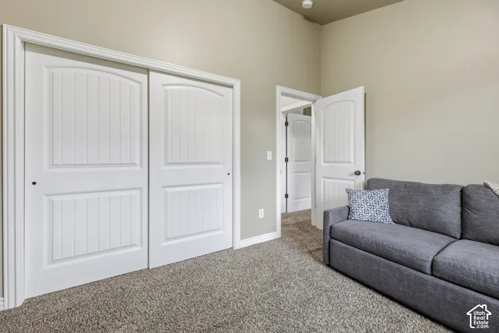 Room featuring high ceilings, wall-to-wall carpeting, sliding panel closet doors, and interior doors with molded detailing