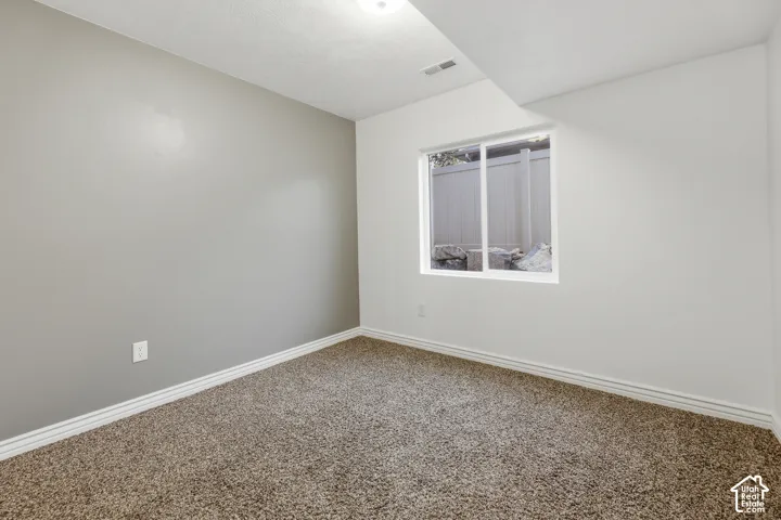Neutral-toned walls featuring a distinct gray accent wall, wall-to-wall carpeting, and a sliding window