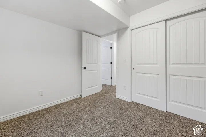 Interior room featuring neutral-tone carpeting, white panel interior doors, and dual sliding closet doors