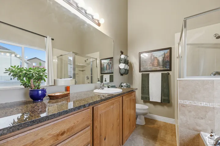 Spa-inspired primary bathroom featuring dual vanities with wood cabinetry, granite countertops, and large framed mirrors