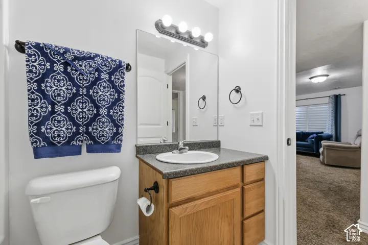 Bathroom vanity featuring wood-finish cabinetry, a neutral countertop, an undermount sink with a chrome faucet, a rectangular wall-mounted mirror, and an overhead four-light fixture