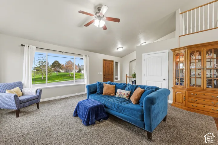 Vaulted ceilings, large picture window, ceiling fan with integrated lighting, built-in cabinetry, and interior balcony railing