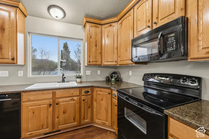 Kitchen featuring wood cabinetry, stone-finish countertops, an integrated microwave, a range, and a double-basin sink