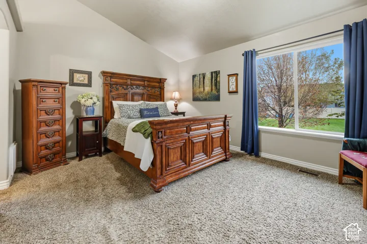 Room featuring a vaulted ceiling, neutral wall tones, textured carpeting, and a large window