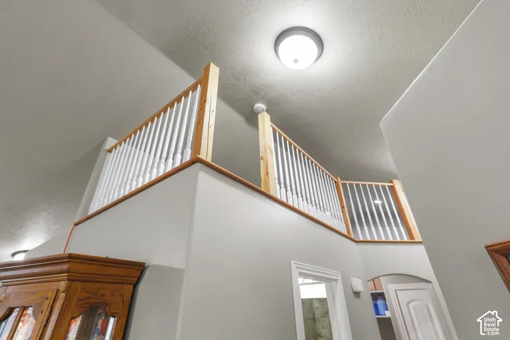 Elevated mezzanine featuring a natural wood-finish handrail and crisp white vertical balusters under a vaulted ceiling. Sellers used it as a space for their grandchildren to hide, but can also be used as storage.