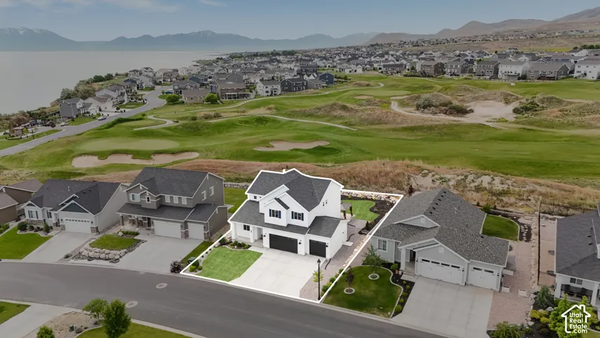 Two-story residence featuring a white exterior, dark-toned shingle roof, attached three-car garage, manicured front lawn, and hardscaped driveway