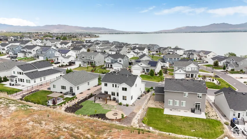 Aerial perspective featuring residential lots with manicured lawns, stone-paver hardscaping, built-in circular fire pits, and mountain-adjacent scenery