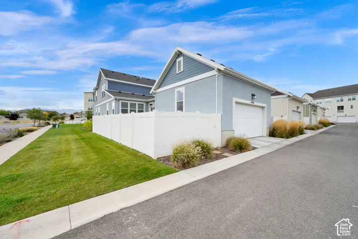 Stucco and horizontal lap siding exterior with a white vinyl privacy fence, single-car garage, and manicured lawn