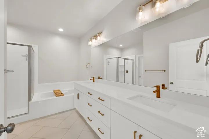 Double vanity featuring white cabinetry, quartz countertops, dual rectangular undermount sinks, metallic fixtures, and a wall-to-wall mirror, complemented by a separate soaking tub and a walk-in shower with a glass enclosure