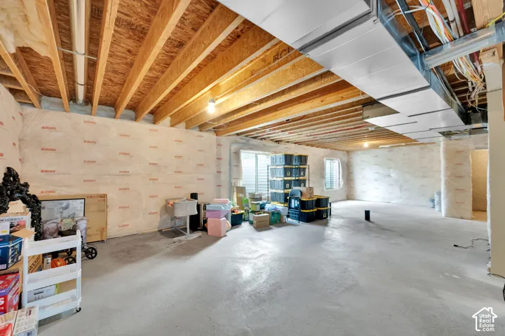 Unfinished lower level featuring exposed wood joist ceilings, concrete flooring, insulated wall paneling, metal HVAC ductwork, and window egress points
