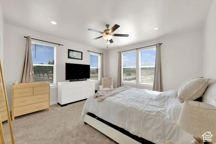 Neutral-toned carpeted flooring, recessed lighting, and a central ceiling fan with integrated light fixture