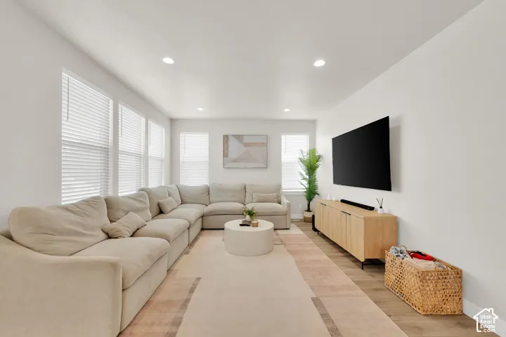 Neutral-toned interior featuring wood-finish flooring, recessed lighting, and multiple windows with horizontal blinds