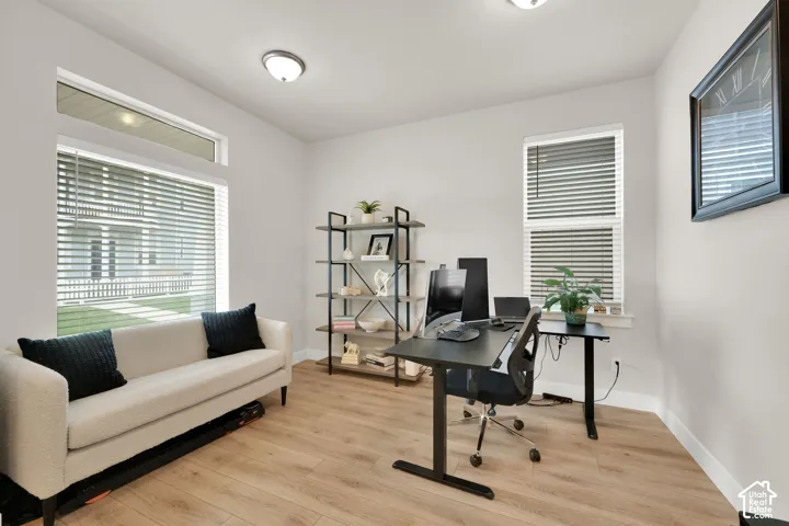 Neutral-toned interior featuring wood-finish flooring, dual-pane windows, transom window detailing, and flush-mount ceiling lighting