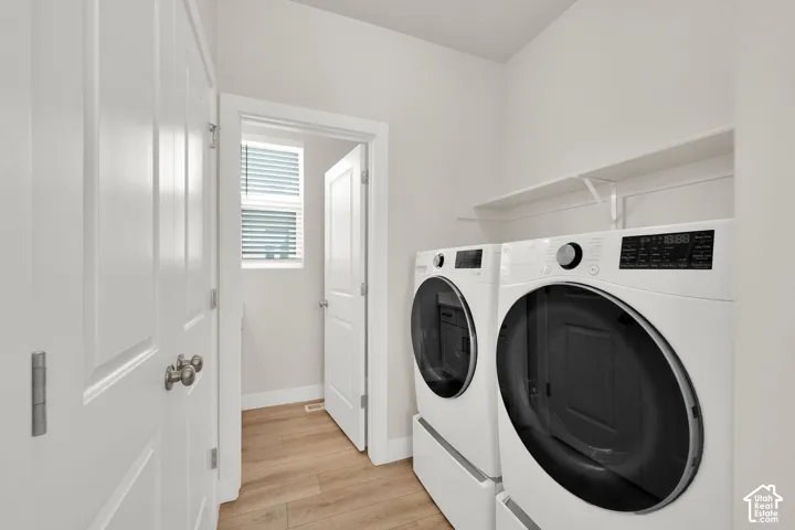 Laundry room featuring wood-finish flooring, white panel doors, and integrated overhead shelving