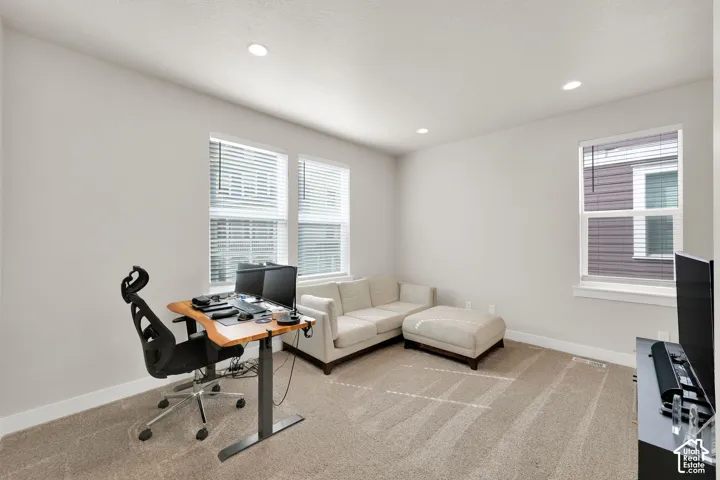 Interior room featuring neutral wall tones, plush wall-to-wall carpeting, recessed ceiling lighting, and multiple windows with horizontal blinds