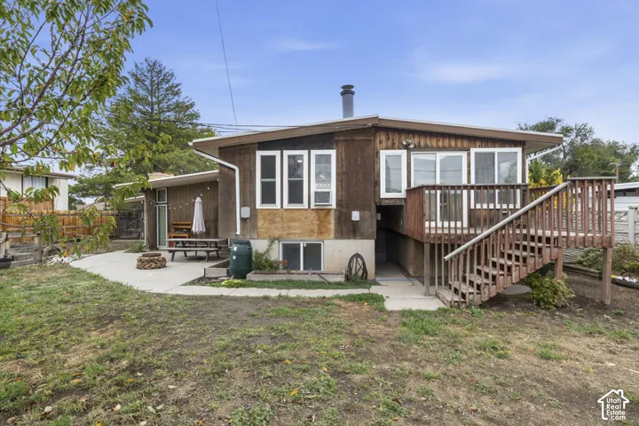 Rear exterior featuring wood siding, an elevated wood deck with stairs, and a concrete patio