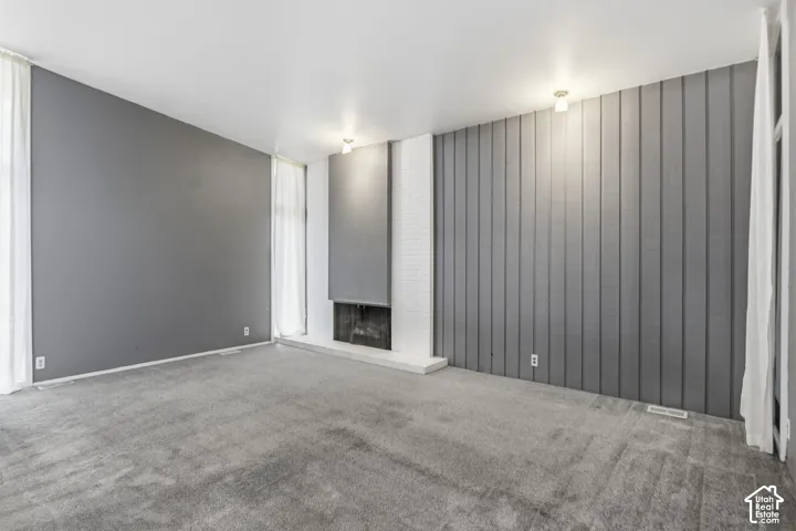 Living area featuring a vertical wood-paneled accent wall, painted brick fireplace surround, hearth, and recessed ceiling lighting