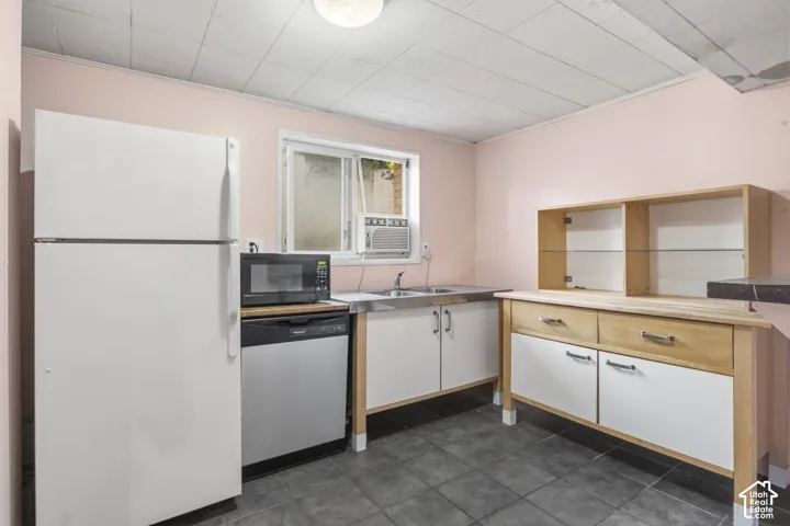 Kitchen area featuring tile flooring, white cabinetry with wood-toned frames, a stainless steel sink, a dishwasher, and a built-in hutch with glass shelving