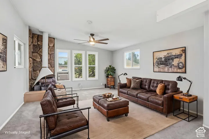 Living room featuring a floor-to-ceiling stone accent wall, sculptural white fireplace, multi-pane windows, and a ceiling-mounted fan