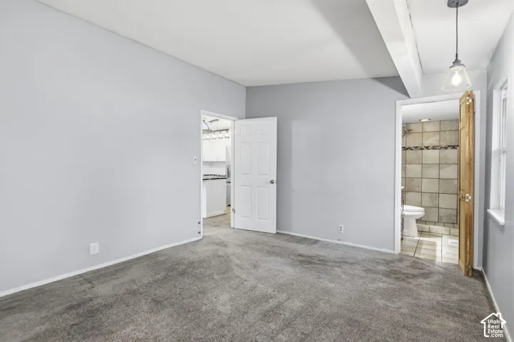 Room featuring neutral walls, wall-to-wall carpeting, and a suspended pendant light fixture with a glass shade