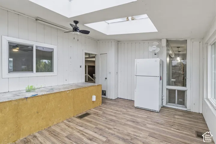 Sun-filled interior featuring skylights, wood-finish flooring, vertical wall paneling, and a built-in counter surface