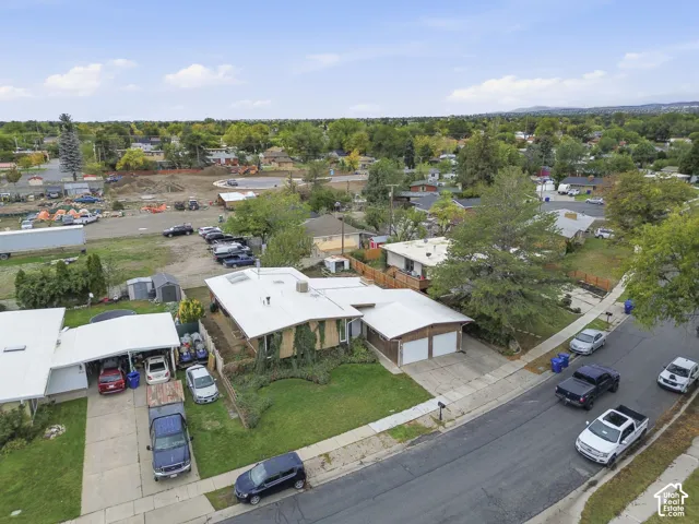 Aerial perspective of a single-story residence featuring a low-pitch roof, an attached two-car garage, an additional detached covered parking structure, and mature landscaping
