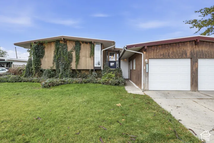 Mid-century modern exterior featuring vertical wood siding, a wide-span roofline, multi-pane windows, and an attached two-car garage